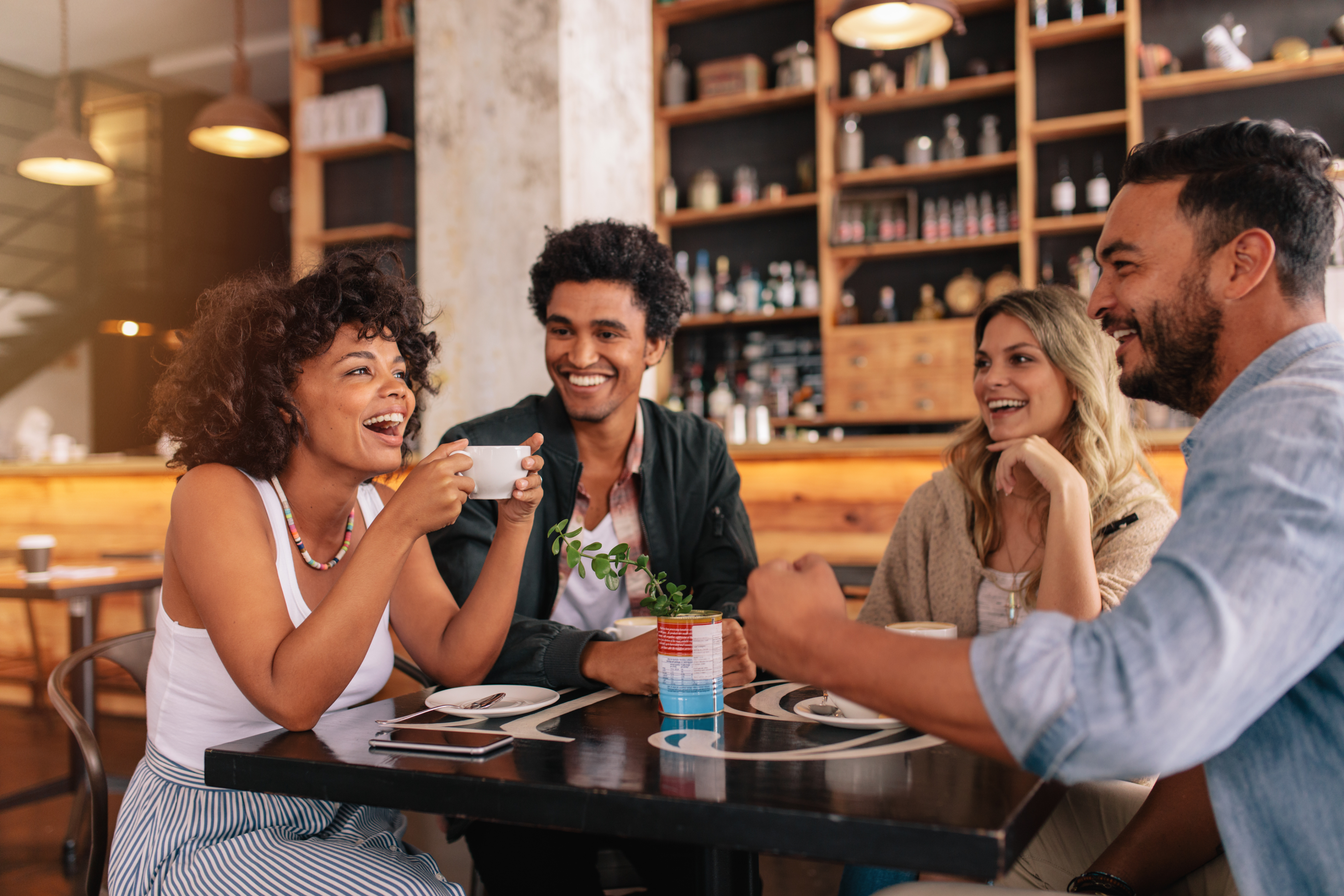 A group of friends siting around a table together and having coffee