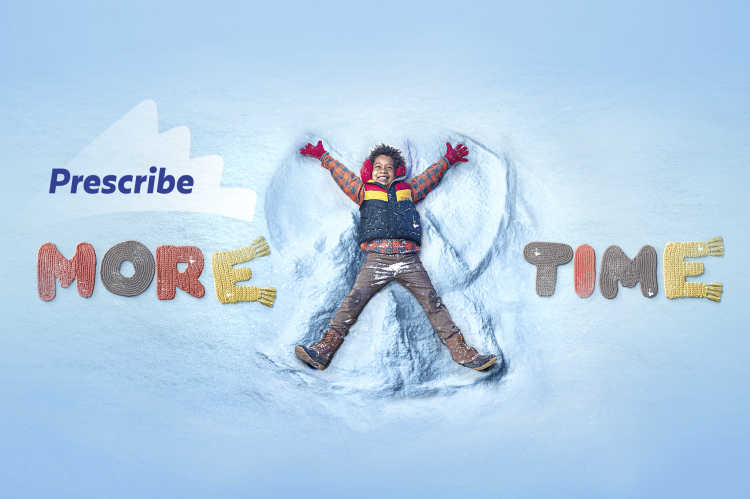A smiling child making a snow angel. The words &quot;Prescribe More Time&quot; are shown to the side.