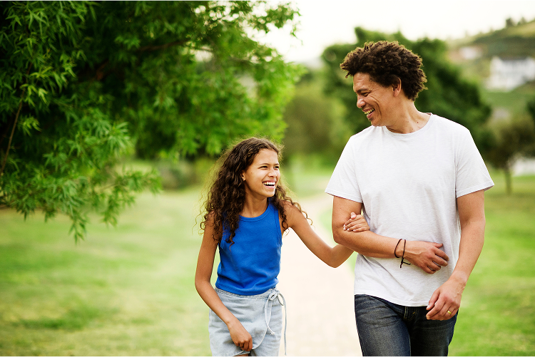 A young girl wrapping her hand around her dad's arm and smiling