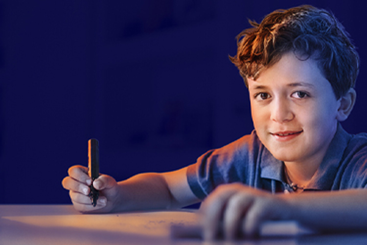 A young boy writing at his desk and smiling