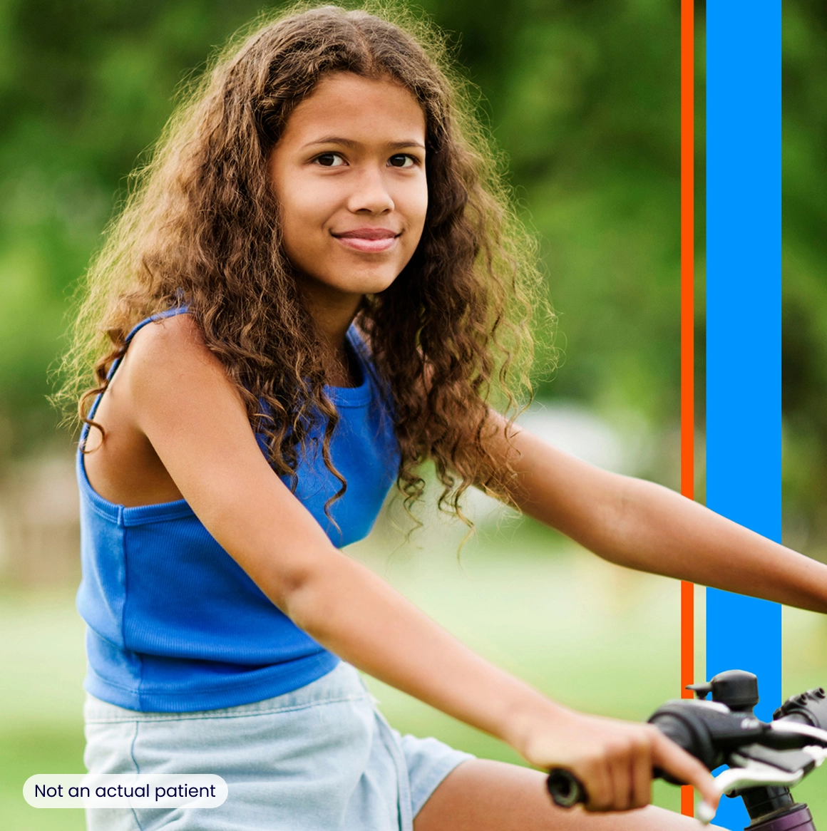 A young girl holding the handlebars on her bicycle and smiling