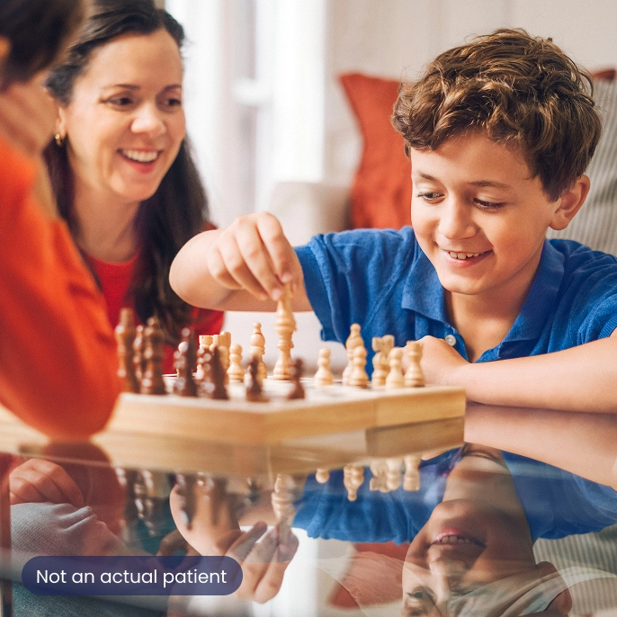 A young boy playing chess with his family